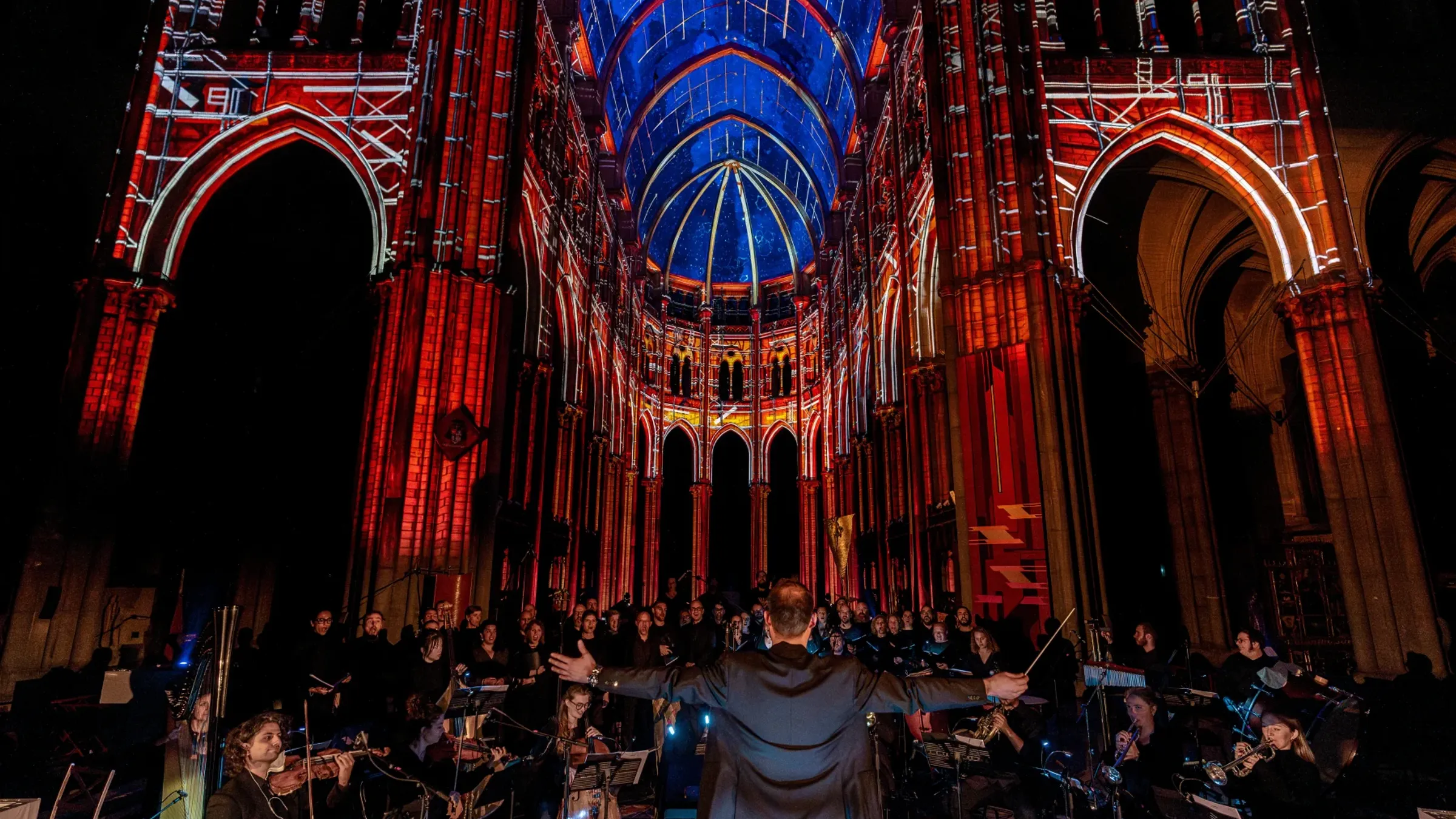 a group of people in a room with a large building with arches and a blue and red light with Sainte-Chapelle in the background
