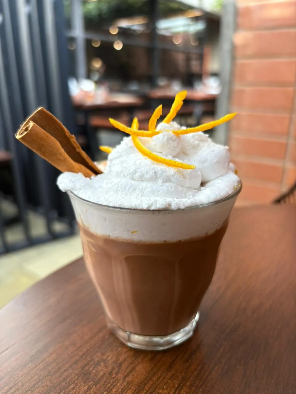 a glass of hot chocolate with whipped cream and cinnamon sticks