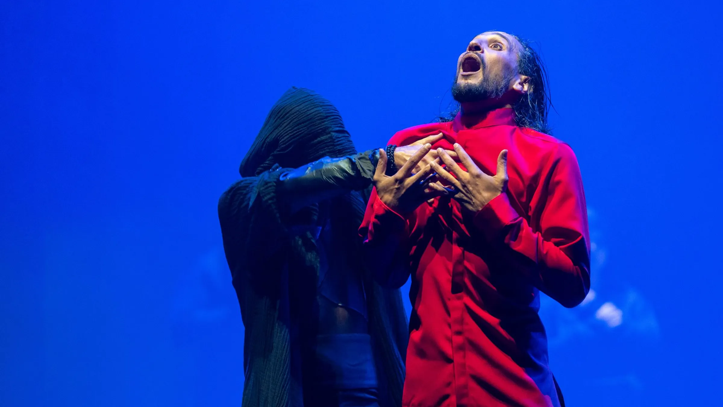 a man in a red shirt with his hands on his chest
