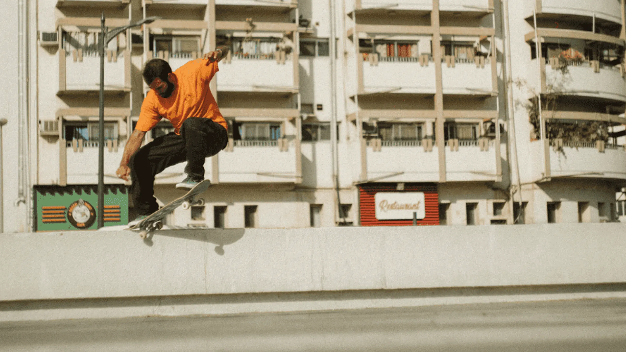 a man in an orange shirt riding a skateboard