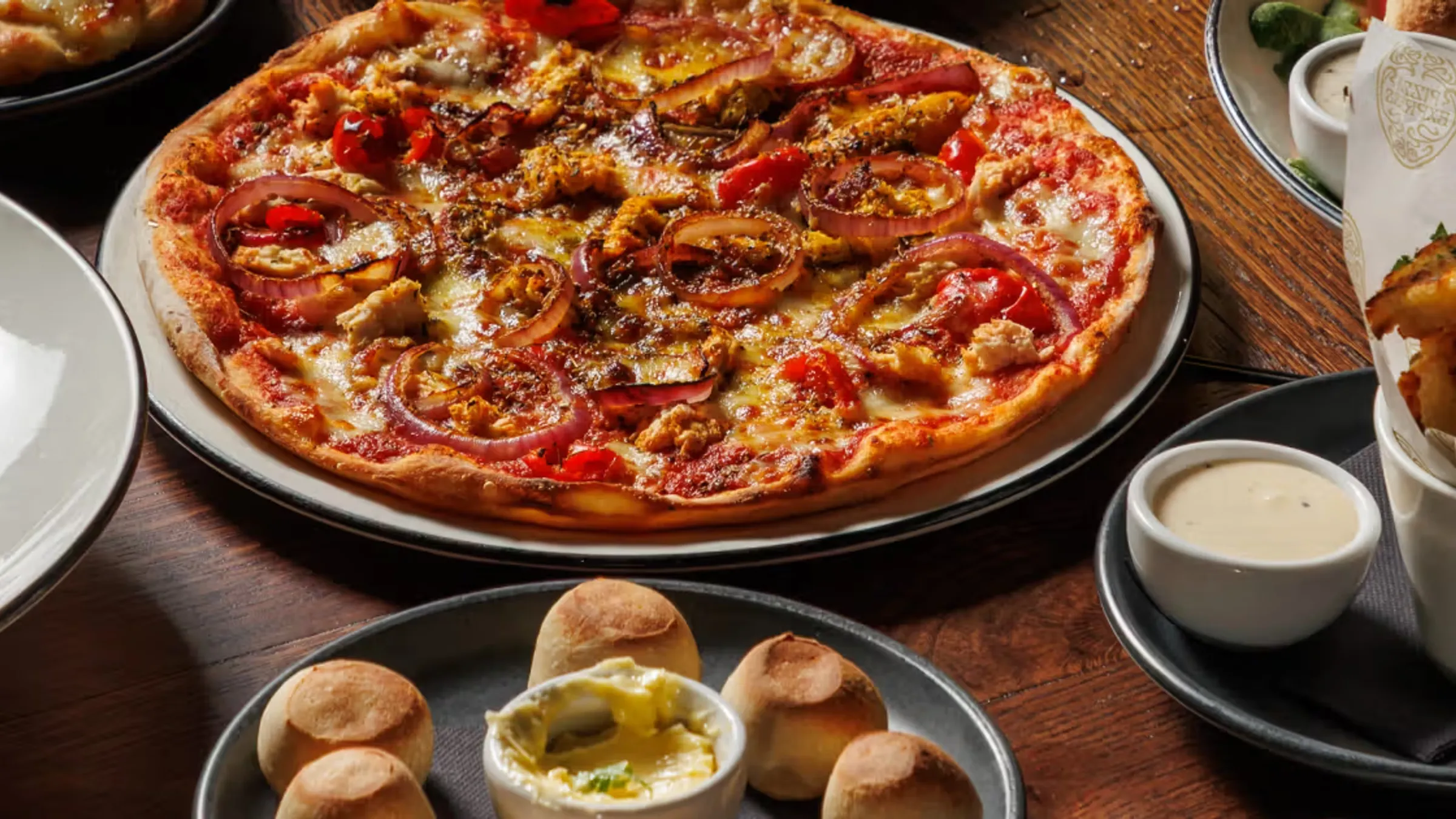 a pizza with onions and tomatoes on a plate