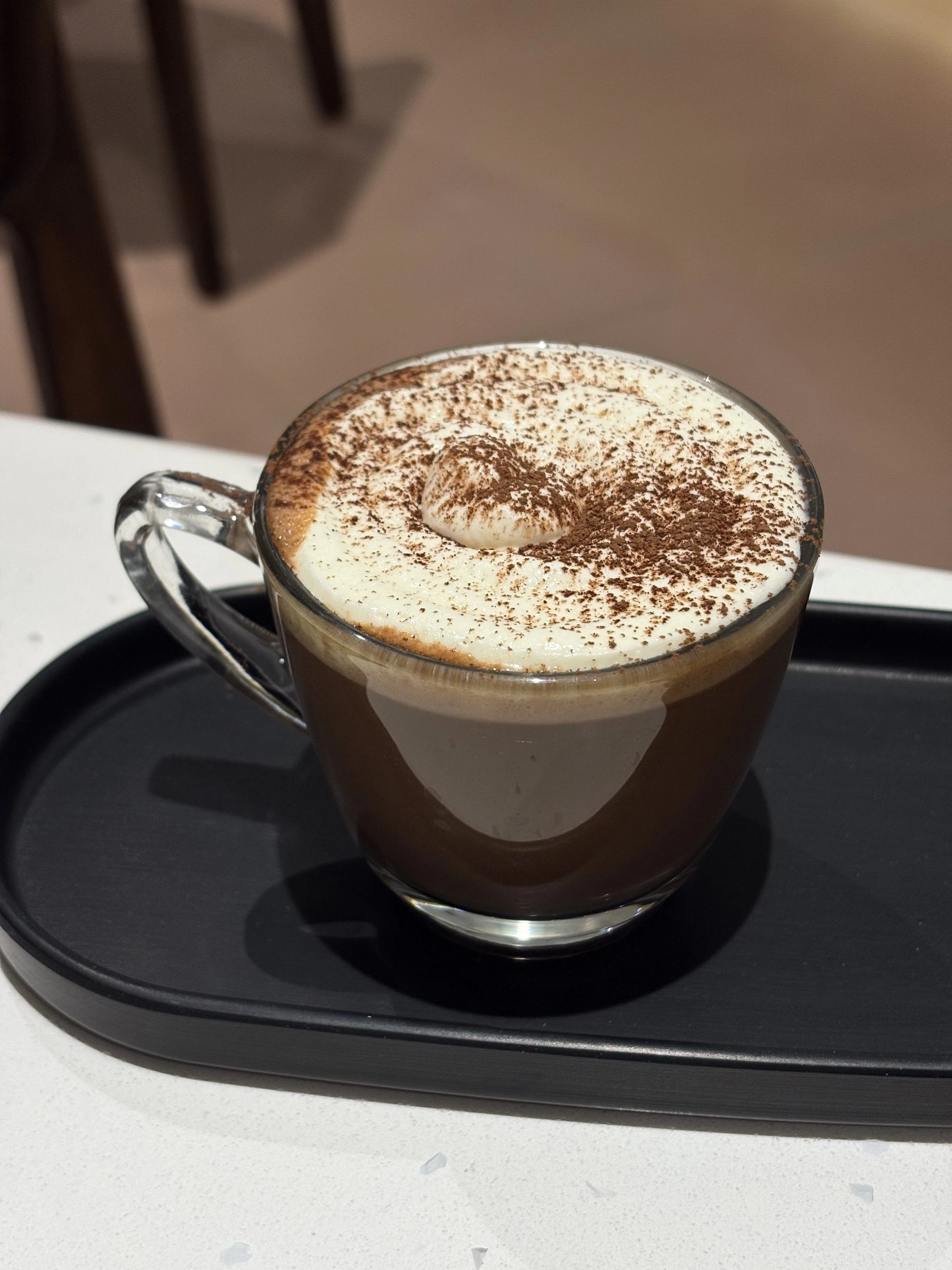 a cup of coffee with a white foam and sprinkles on top