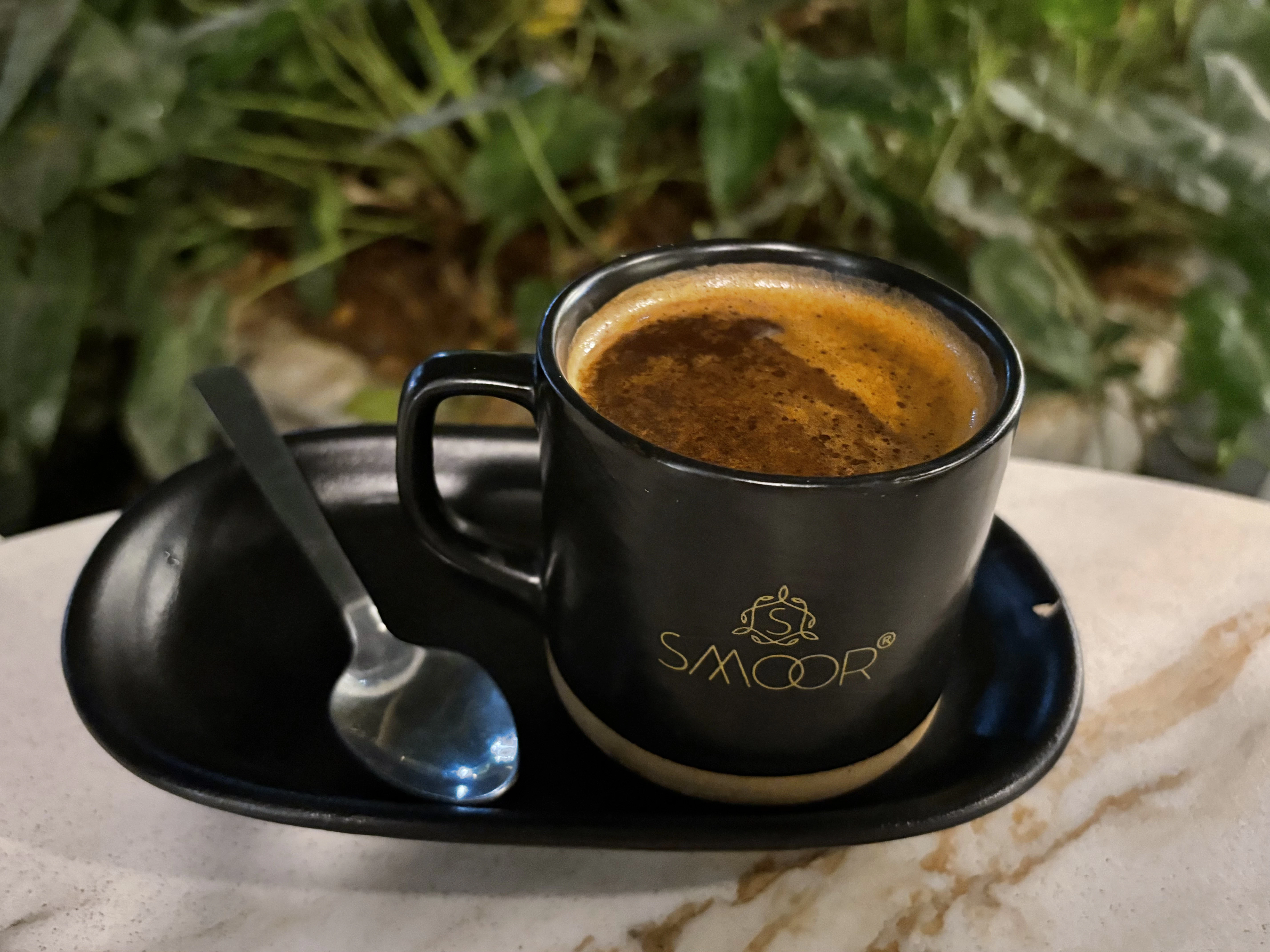 a cup of coffee on a plate with a spoon
