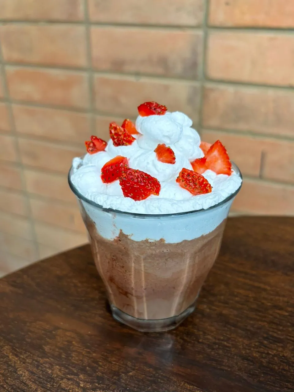 a glass of chocolate milkshake with strawberries and whipped cream