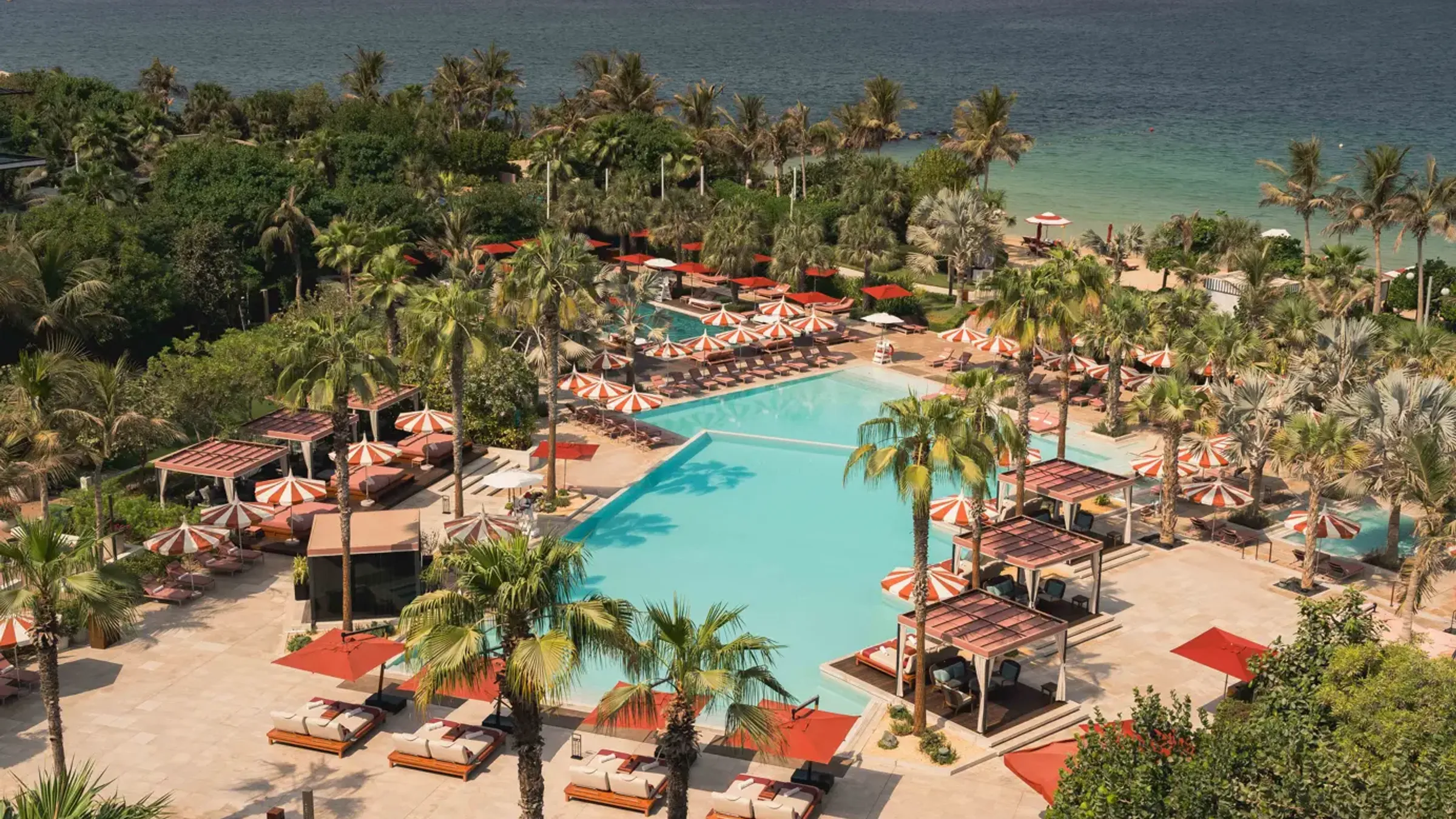 a pool with umbrellas and chairs on a beach