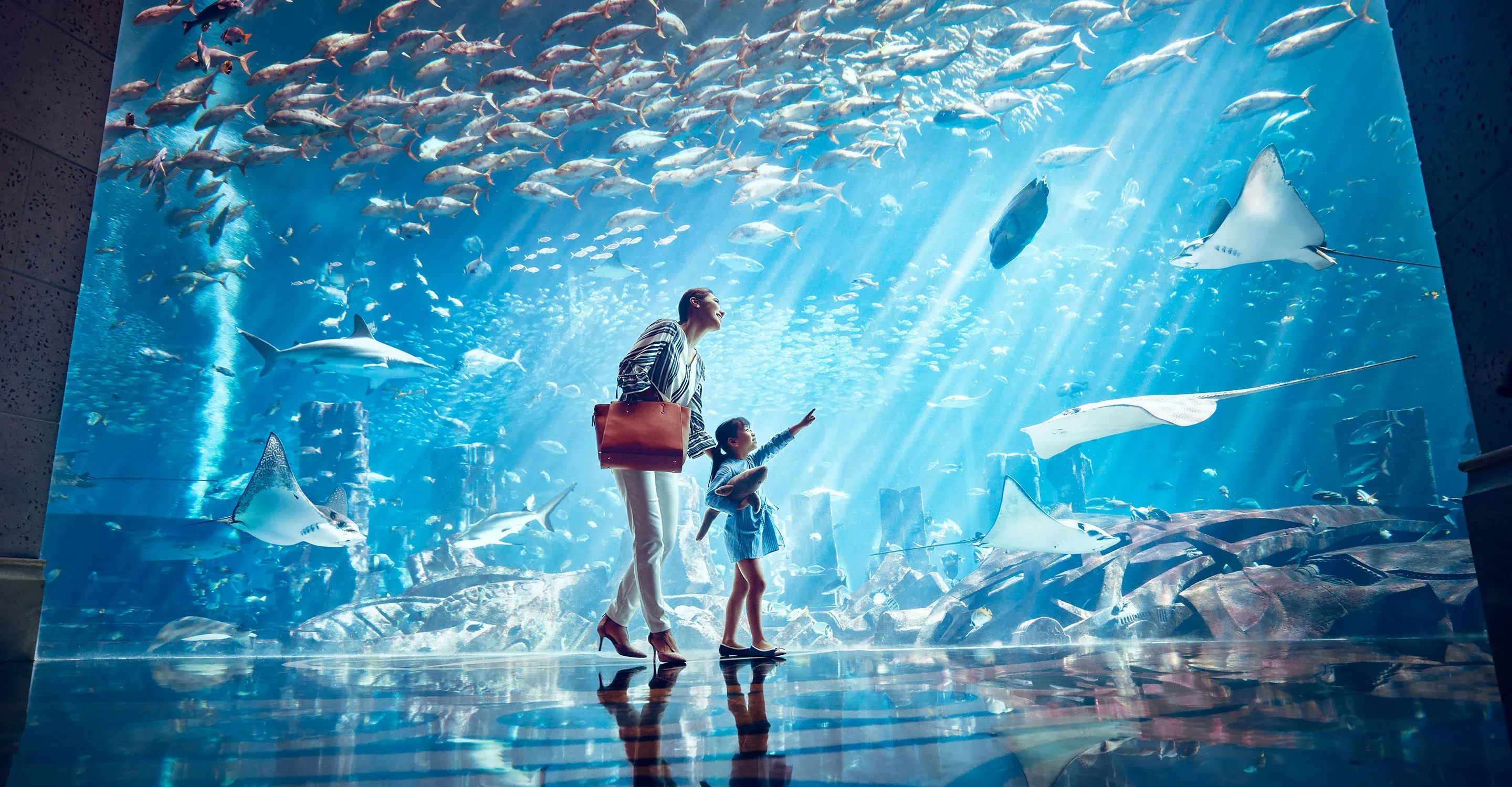 a woman and a girl looking at fish in an aquarium