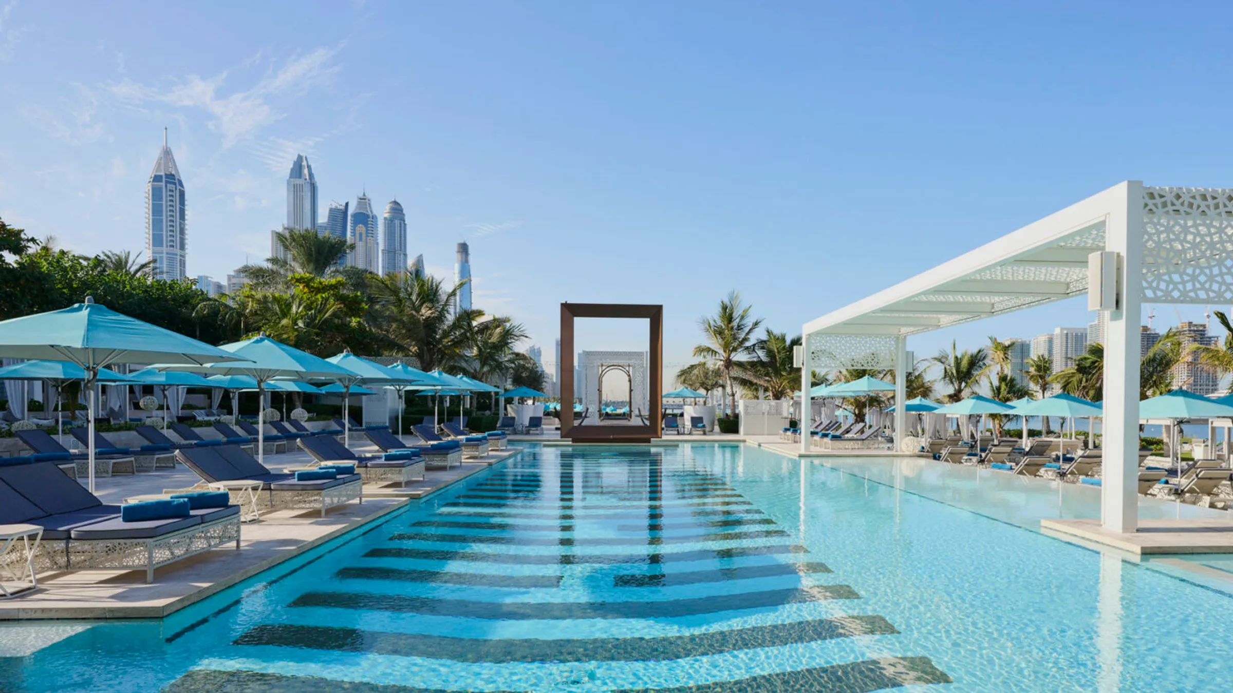 a swimming pool with blue umbrellas and chairs