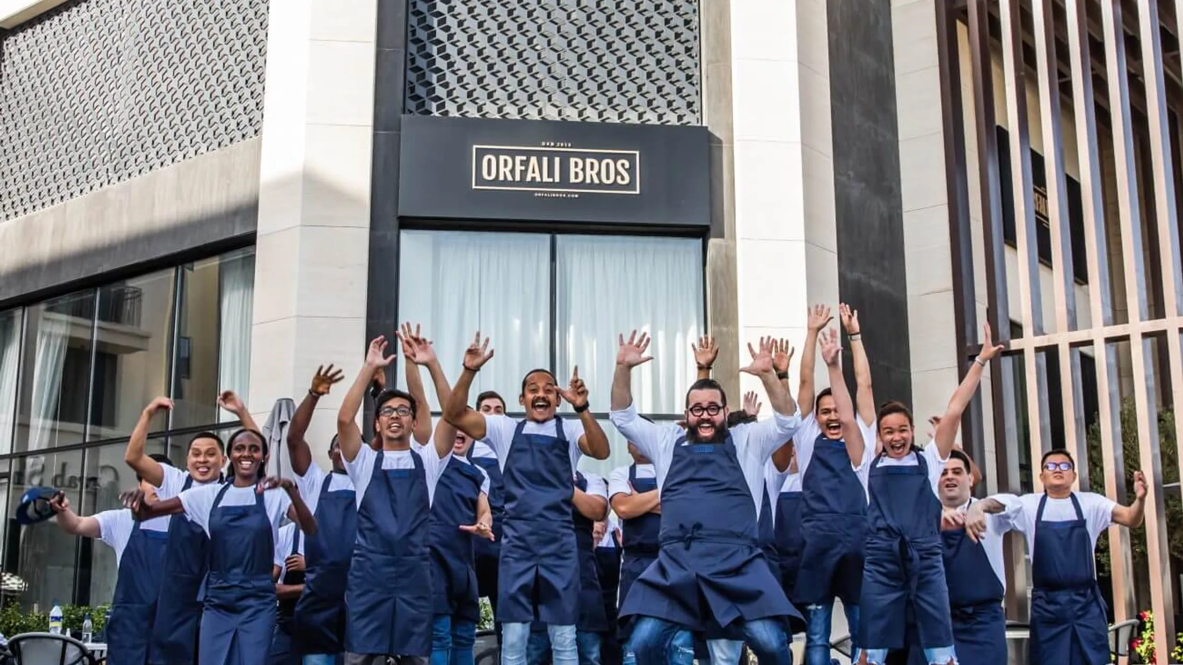 a group of people wearing aprons jumping in front of a building