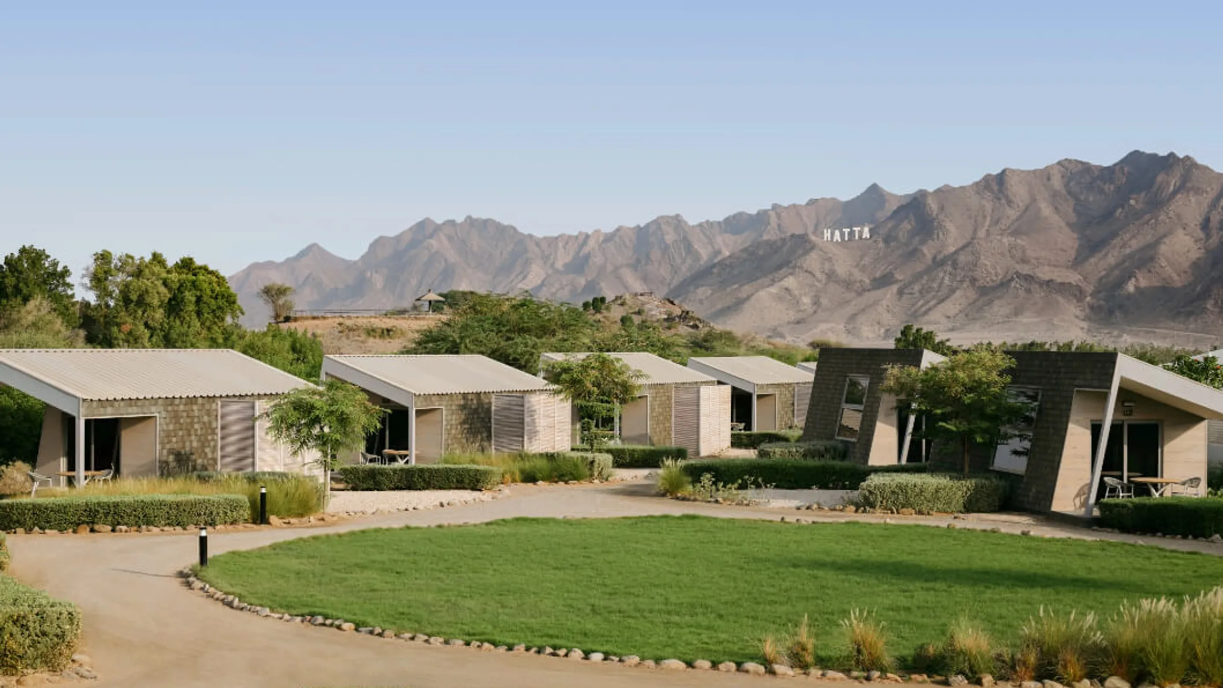 a group of houses with a lawn and mountains in the background
